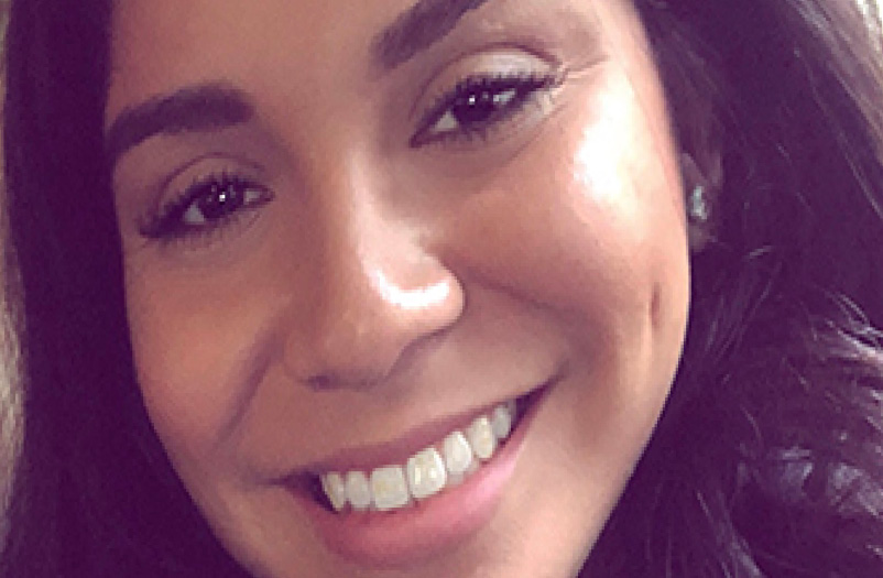 A closeup of a young woman smiling with dark hair.